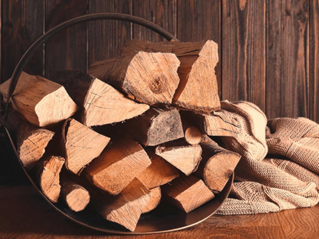 Ovntørret brænde stablet i kurv klar til brug ved pejs eller brændeovn